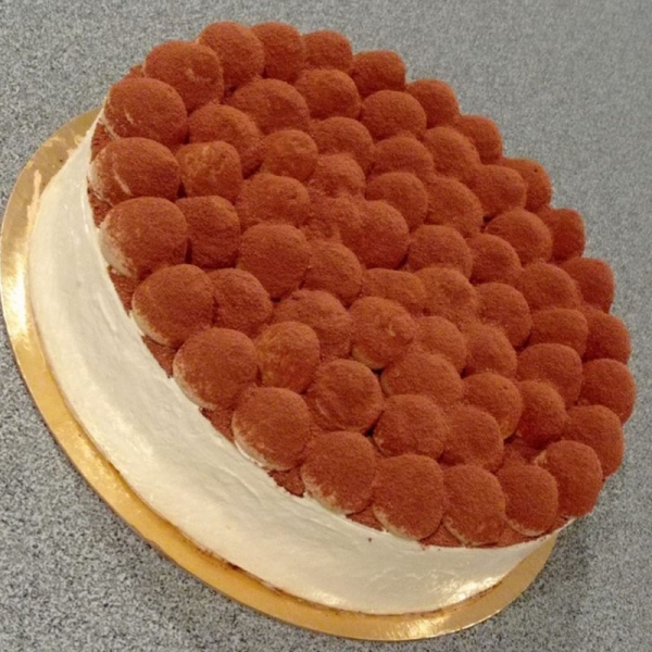 Entremets tiramisu avec crème visible sur le pourtour et dessus du gâteau en petits dômes ganache café saupoudrés de cacao